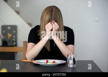 ©PHOTOPQR/L'ALSACE/Vanessa MEYER ; ; 02/06/2021 ; Une jeune fille tient sa tête entre ses mains devant une assiette presque vide avec une tomate cerise et une rondelle de concombre. Les troubles du comportement alimentaire ont augmenté pendant la crise sanitaire. - anorexia Stock Photo