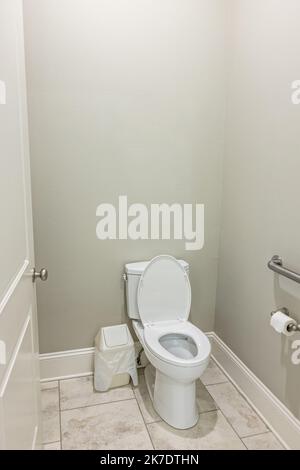 A small half bathroom with gray walls and a toilet with tile floors in a new construction house Stock Photo