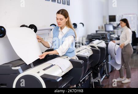Print worker controlling printing process on modern offset machine in print shop Stock Photo