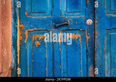 Old wooden blue painted and textured door, with rusty metal hinge Stock Photo