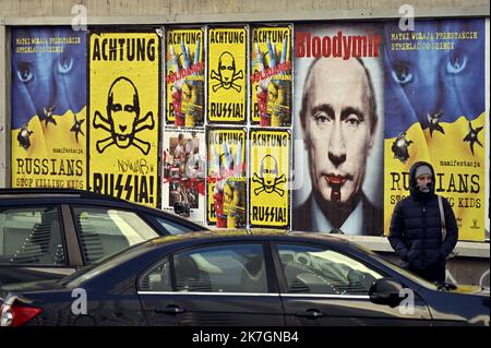 ©PHOTOPQR/L'EST REPUBLICAIN/Alexandre MARCHI ; WARSAW ; 11/03/2022 ; GUERRE EN UKRAINE - CONFLIT - RUSSIE - RUSSIA - PUTIN - POUTINE - POSTER - WAR IN EUROPE - SS. Varsovie 11 mars 2022. Une personne passe près d'affiches anti-Poutine collées sur un mur, de la rue Nowogrodzka, avec les inscriptions suivantes 'Russians stop killing kids', 'Achtung Russia (Vladimir Poutine représenté en tête de mort)' et 'Bloodymir avec le portrait de Poutine où coule du sang de sa bouche'. PHOTO Alexandre MARCHI. Warsaw (POLAND) March 11, 2022. A person walks past an anti-Putin poster on a wall in Nowogrodzka  Stock Photo