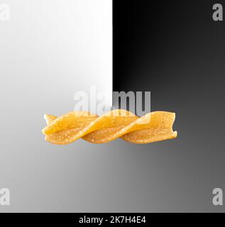 A single piece of fusilli pasta in a composite picture with a black and white knife edge Stock Photo