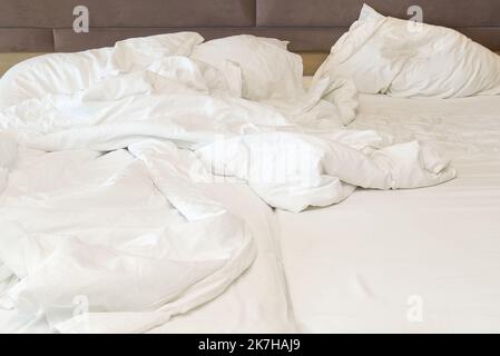 wrinkled bed after a stormy night of love. Closeup on soft white and crumpled blanket in bedroom Stock Photo