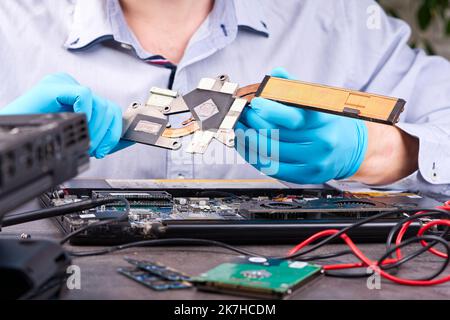 Hands fixing motherboard of pc or laptop notebook close up in service. Laptop repair service. Stock Photo