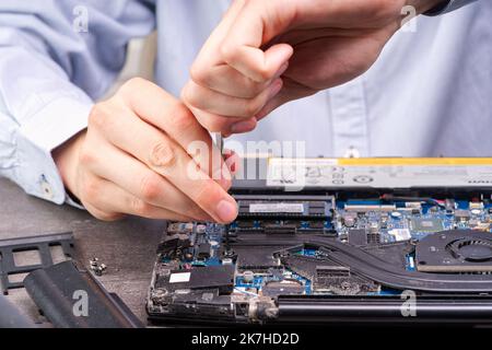 Man disassembles a laptop. Computer service and repair concept. Laptop disassembling in repair shop Stock Photo