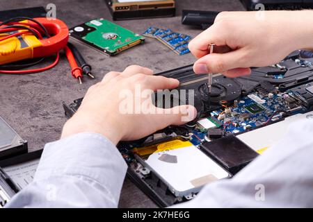 Hands fixing motherboard of pc or laptop notebook close up in service. Laptop repair service. Stock Photo
