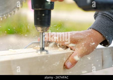 Crpenter builder working overall equals a wooden bar with a milling machine in the workshop Stock Photo