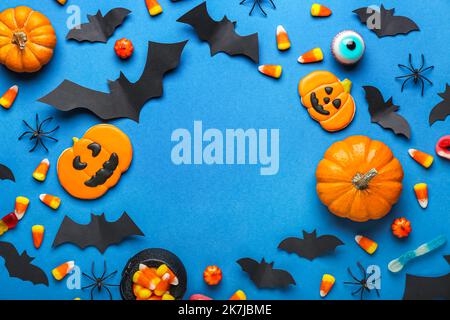Frame made of Halloween treats, paper bats and spiders on blue background Stock Photo
