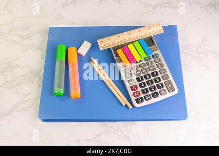 blue folder and writing equipment with Calculator, highlighter, pencil, ruler, eraser on the white table at the office Stock Photo