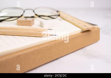 close up a pencil with pencil sharpener on paper and eraser rule, glasses on background (Selective focus pencil) Stock Photo