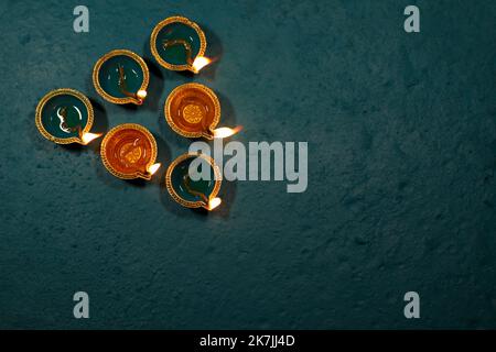 Happy Diwali Festival of Lights teal color background with teal and golden color traditional clay oil lamps Diya lit during Deepavali celebration. Stock Photo