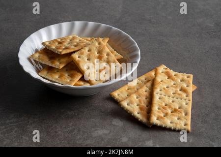 Crackers in a dish set against a dark stone background. Close-up. Stock Photo