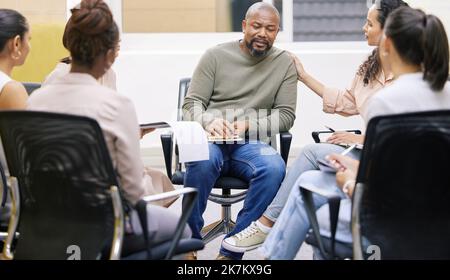 Were here for you. a group of businesspeople having a casual meeting in a boardroom and showing support to their coworker. Stock Photo