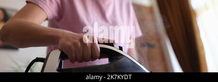 Woman irons clothes with iron on ironing board Stock Photo