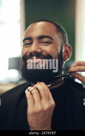 The world isnt ready for this handsome face. a handsome young man sitting and getting his beard styled by his hairdresser. Stock Photo