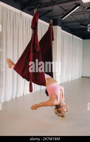 Premium Photo  A young girl an aero yoga coach is hanging on a hammock in  the yoga club hall a woman in pink sportswear is doing antigravity yoga