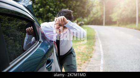 Asian businessman car broken has problems with car down during go to work in morning he pushing out of gas on road at countryside, business man have t Stock Photo