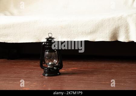 An old black kerosene lamp stands on the floor of a house during the day Stock Photo