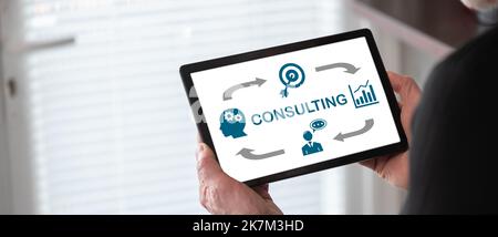 Consulting concept shown on a tablet held by a man Stock Photo