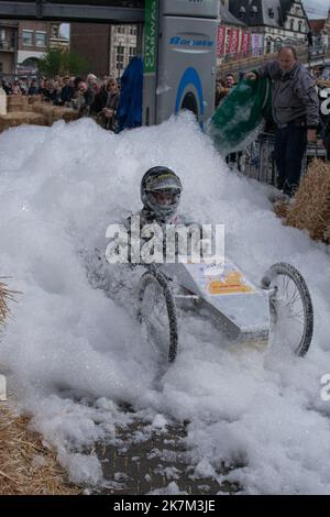 Sint Niklaas, Belgium, 05 May 2019, Young man drives a custom three wheel go-kart through a mountain of foam during a soap box race Stock Photo