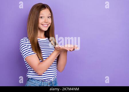 Photo of satisfied glad pleasant girl straight hairdo striped t-shirt palms demonstrating empty space isolated on purple color background Stock Photo
