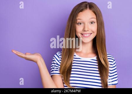 Photo of optimistic satisfied girl straight hairdo dressed striped t-shirt demonstrating empty space isolated on purple color background Stock Photo