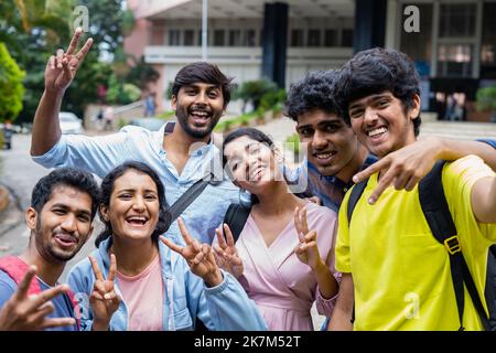 Group of smiling college students taking selfie by holding camera at college campus - concept of friendship, education and success. Stock Photo