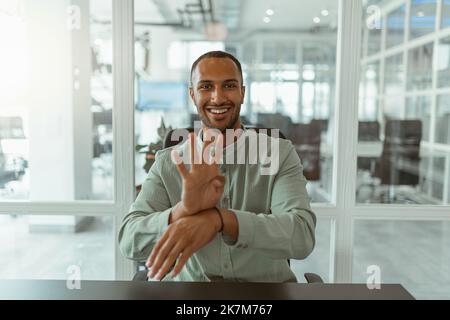 African businessman using sign language while talking online with client sitting in office Stock Photo