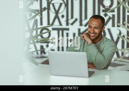Smiling african businessman working laptop while sitting in modern coworking Stock Photo