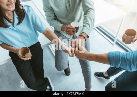 Smiling group of multiethnic colleagues drinking coffee and talking during break Stock Photo