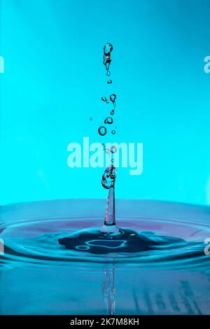 Close-up water drops falling and impacting a body of water. Stock Photo