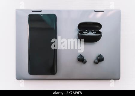 A Laptop computer, Headphones and a Smartphone on a wooden Desktop. Stock Photo