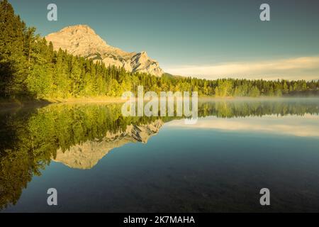 Trees Reflecting in Wedge Pond in the golden hour, Canadian Rockies, Alberta, Canada Stock Photo