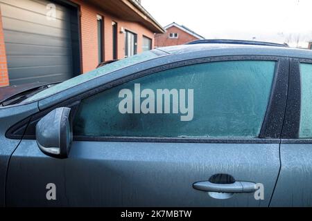 A portrait of the side of a car which completely frozen. The driver side window is frozen shut. The ice first needs to melt or be removed before the d Stock Photo