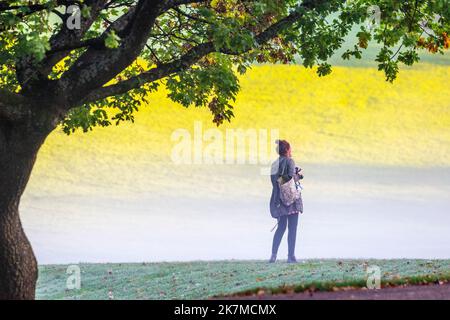 Preston, Lancashire.  UK Weather;  18 Oct 2022. The sun rises over the River Ribble as local residents take light exercise at dawn along Riverside walk, a cold misty foggy start to the day.  Avenham park family space, cycling routes and walking trails in the north-west of England. Credit; MediaWorldImages/AlamyLiveNews Stock Photo