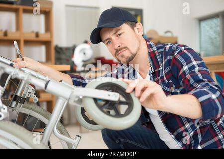 man repairing a wheelchair in workshop Stock Photo