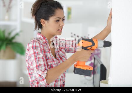 young woman using a drill Stock Photo