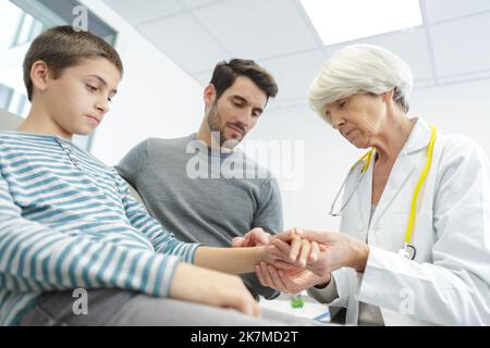 senior female doctor examining child next to his kids Stock Photo