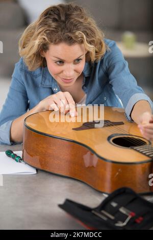 young woman is repairing guitar strings Stock Photo