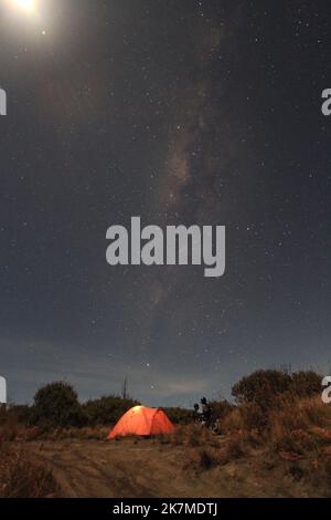 Tent and milkyway trail under the moonlight in Indonesia Stock Photo