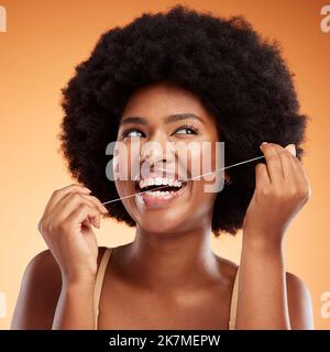 Flossing, dental and black woman cleaning teeth against an orange studio background. Young, African and thinking model with idea while getting results Stock Photo