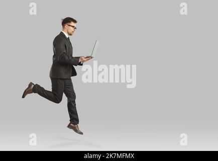 Male professional executive manager or financier who jumps with laptop symbolizing career growth. Stock Photo