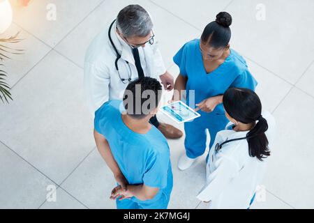 Doctor, nurse and conversation with tablet from above, medical team meeting in hospital lobby for discussion. Healthcare, men and women doctors Stock Photo