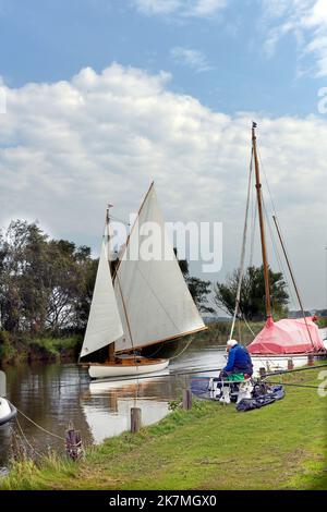 fisherman and traditional broads sailing boat on river thurne martham norfolk england Stock Photo