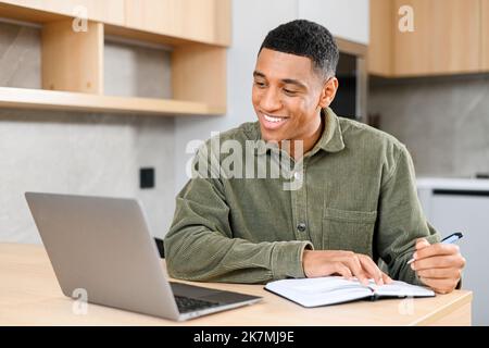Concentrated latin student looking at the laptop display, solving business tasks, looking for new ideas while writing something at the notebook. People and technologies concept Stock Photo