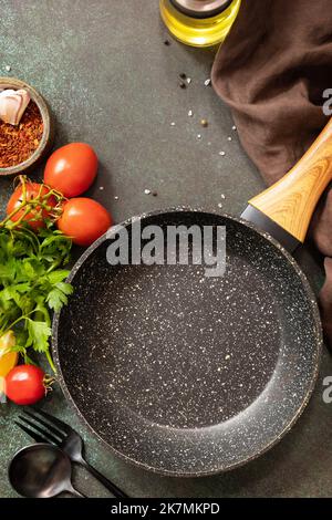 Food cooking background with Frying pan. Empty skillet, vegetables, spices and herbs on dark table background. View from above. Copy space. Stock Photo