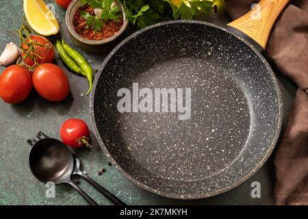 Food cooking background with Frying pan. Empty skillet, vegetables, spices and herbs on dark table background. Stock Photo