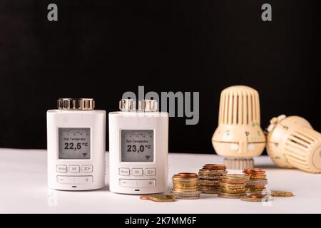 Elektronische Heizungsventile mit  Geldmünzen gegen manuelle Heizungsventile zur Kostensparung Stock Photo