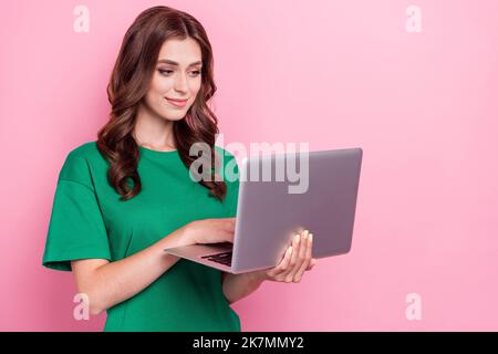 Photo of pretty positive focused woman with wavy hairdo dressed green t-shirt writing email hold laptop isolated on pink color background Stock Photo
