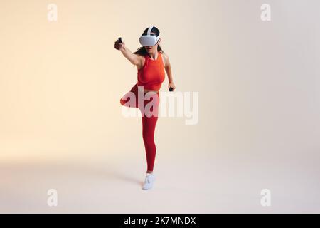 Sporty young woman working out using 3D technology. Athletic young woman exploring a virtual reality fitness game. Young woman wearing virtual reality Stock Photo